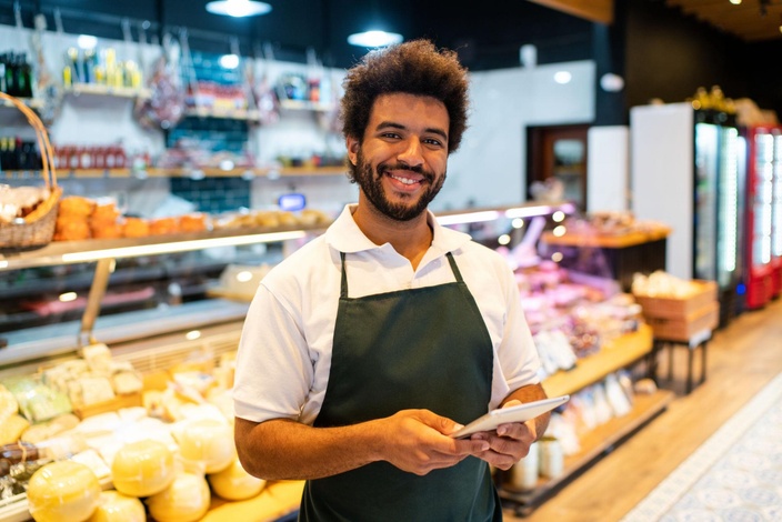 Commerçant en magasin avec une tablette près des produits.